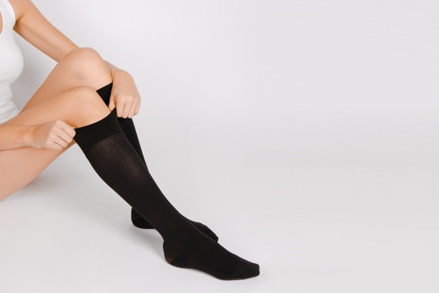 Woman pulling up a pair of black compression socks
