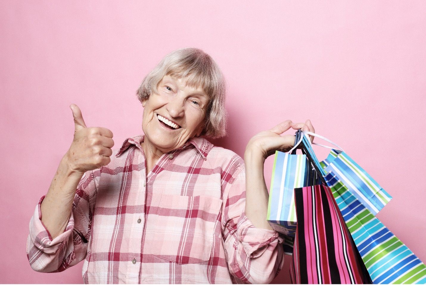 An old woman holding shopping bags smiling